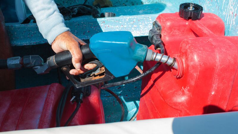 Close-up shot of a man fueling red plastic tank of a vehicle in Charlotte with petrol