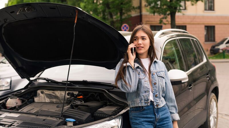 Woman In Jean Jacket Making a Roadside Assistance Call